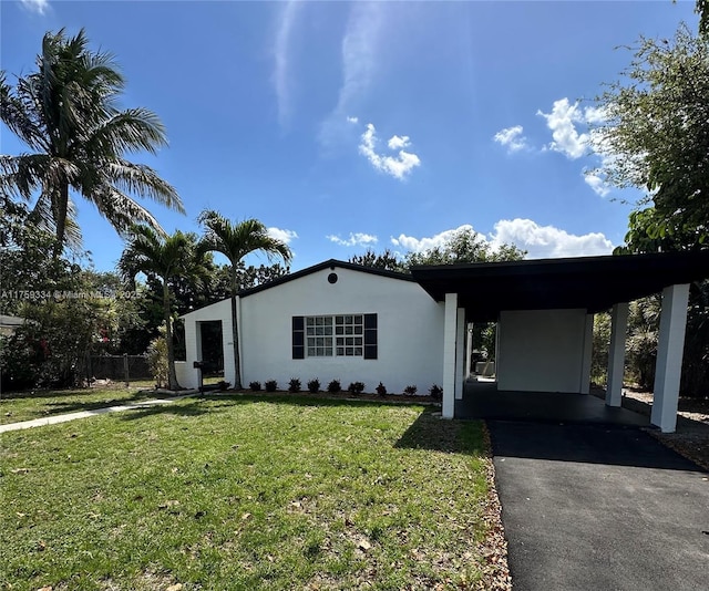 view of front facade featuring driveway, a front lawn, a carport, and stucco siding