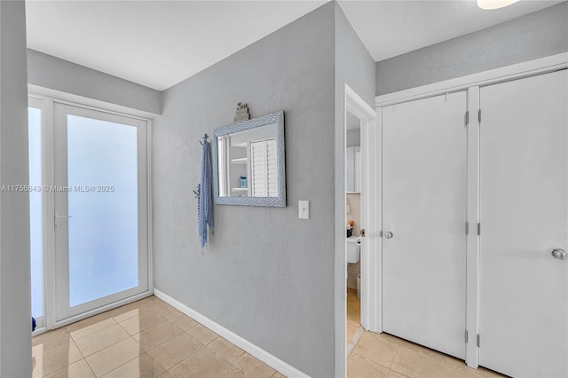 hallway featuring light tile patterned floors and baseboards