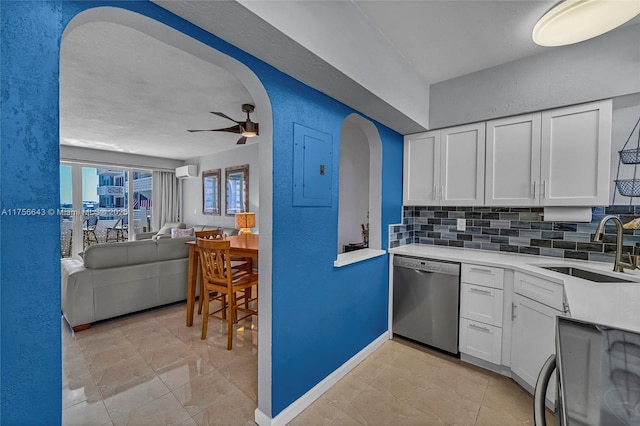 kitchen featuring electric panel, decorative backsplash, stainless steel dishwasher, arched walkways, and a sink