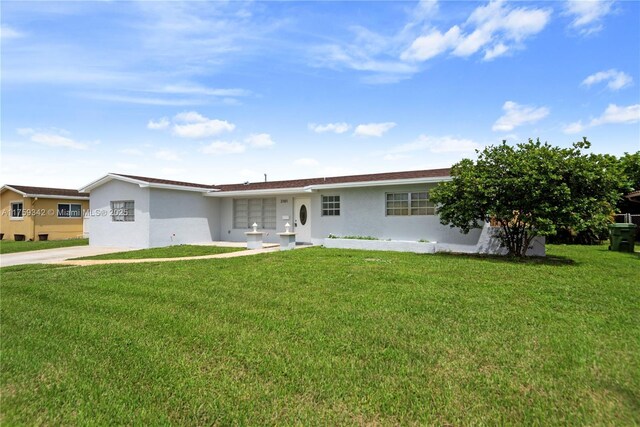 ranch-style home featuring a front lawn, driveway, and stucco siding