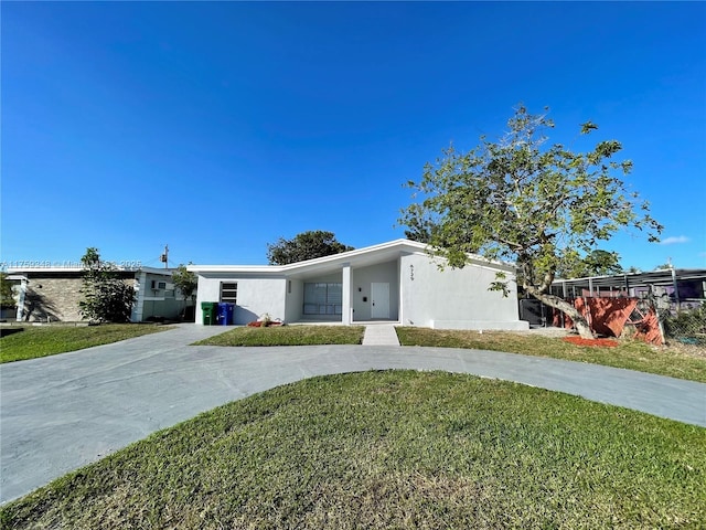 view of front facade with a front yard, concrete driveway, and stucco siding