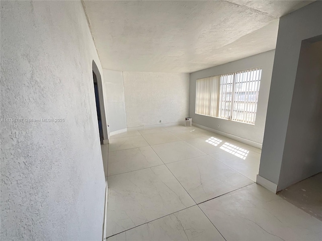 empty room featuring baseboards and arched walkways