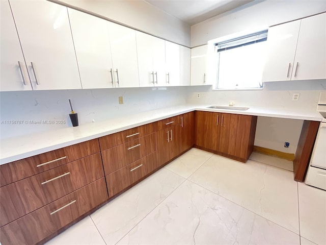 kitchen with white cabinetry, light countertops, decorative backsplash, and a sink