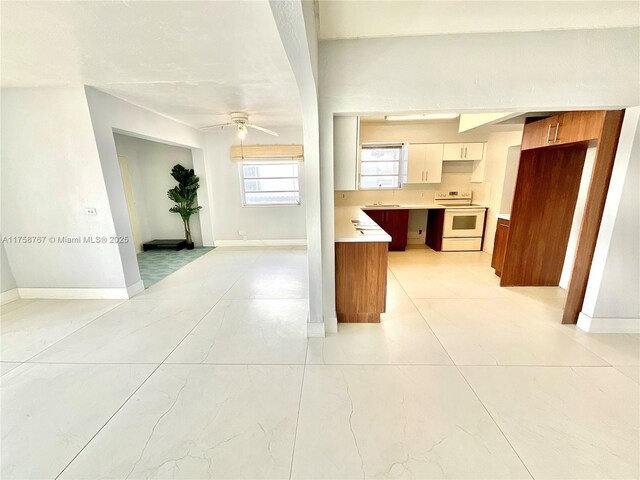 kitchen with white range with electric cooktop, light tile patterned floors, baseboards, and a ceiling fan