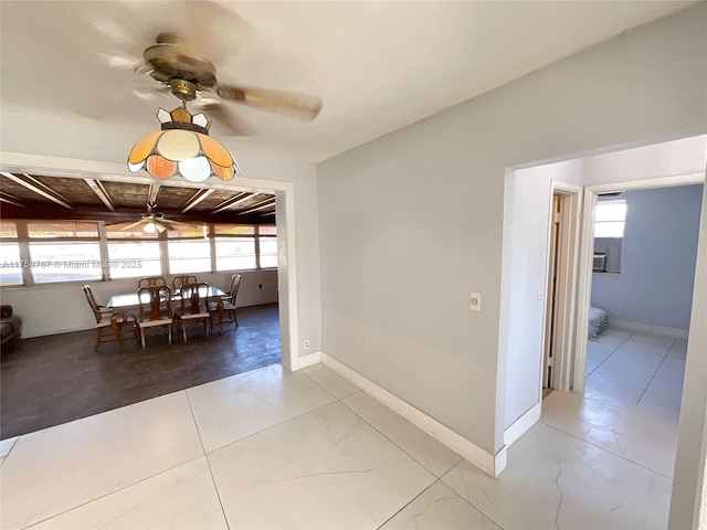 unfurnished dining area featuring a ceiling fan and baseboards