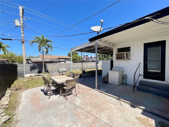 view of patio featuring entry steps, washer / clothes dryer, outdoor dining area, and a fenced backyard