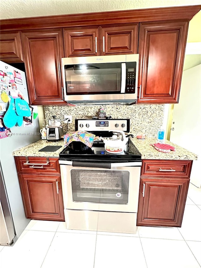 kitchen with dark brown cabinets, appliances with stainless steel finishes, light stone countertops, and tasteful backsplash