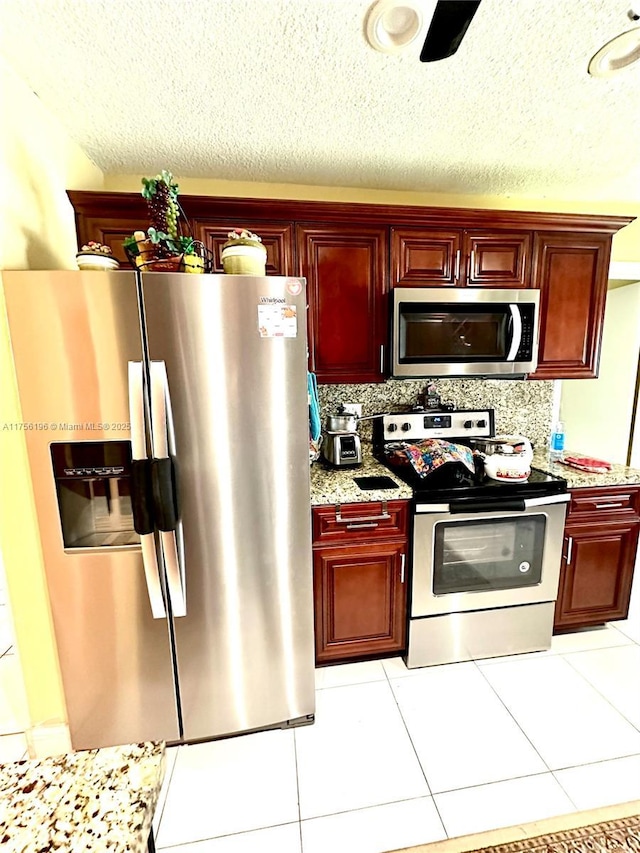 kitchen featuring stainless steel appliances, reddish brown cabinets, light tile patterned floors, and tasteful backsplash