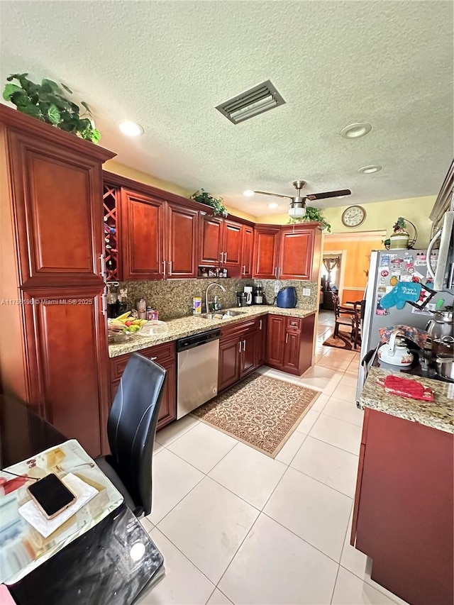 kitchen with light tile patterned flooring, a sink, visible vents, dark brown cabinets, and appliances with stainless steel finishes