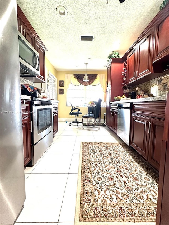 kitchen featuring light tile patterned flooring, visible vents, dark brown cabinets, appliances with stainless steel finishes, and decorative backsplash