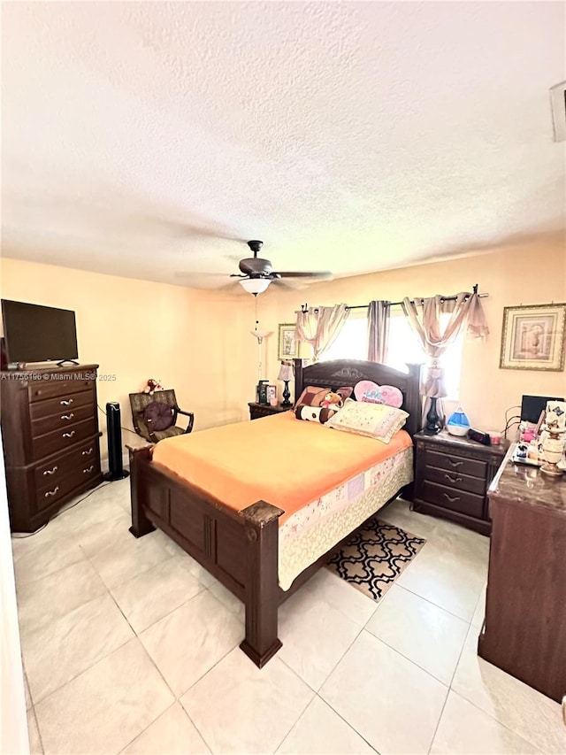 bedroom featuring a textured ceiling, light tile patterned floors, and a ceiling fan