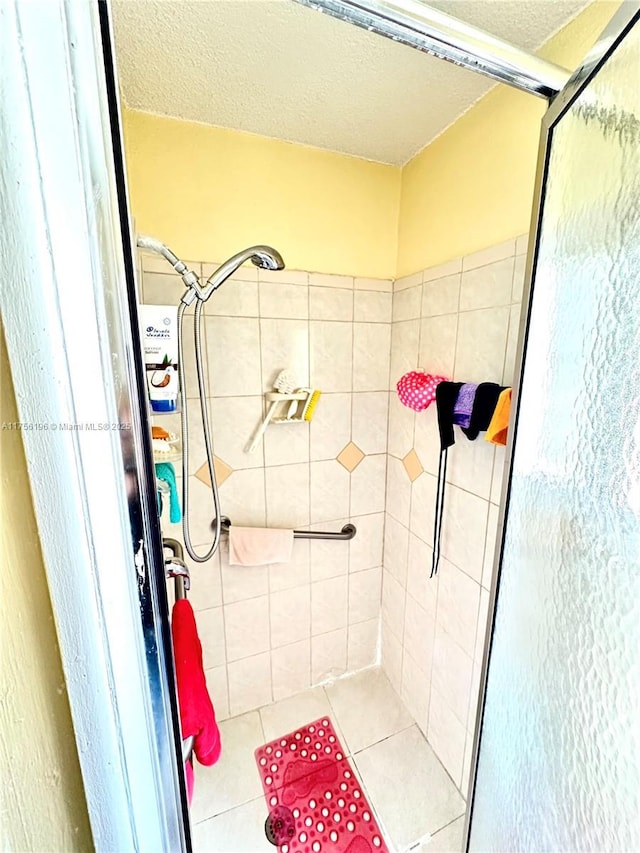 full bathroom with a stall shower, a textured ceiling, and tile patterned floors