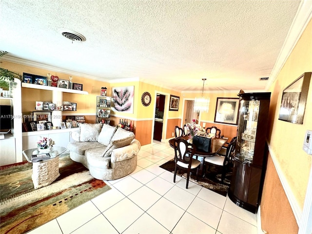 living area featuring ornamental molding, tile patterned flooring, visible vents, and a textured ceiling