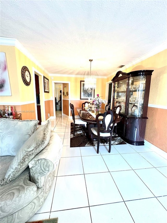 dining area with a textured ceiling, ornamental molding, light tile patterned flooring, and an inviting chandelier