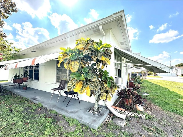 view of side of home featuring a lawn, a patio area, and cooling unit