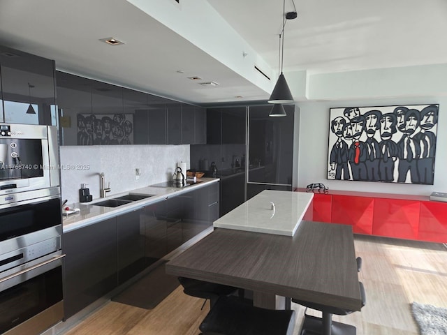 1451 Brickell Ave Unit 1201, Miami, FL 33131 - kitchen featuring modern cabinets, light wood finished floors, dark cabinetry, pendant lighting, and tasteful backsplash