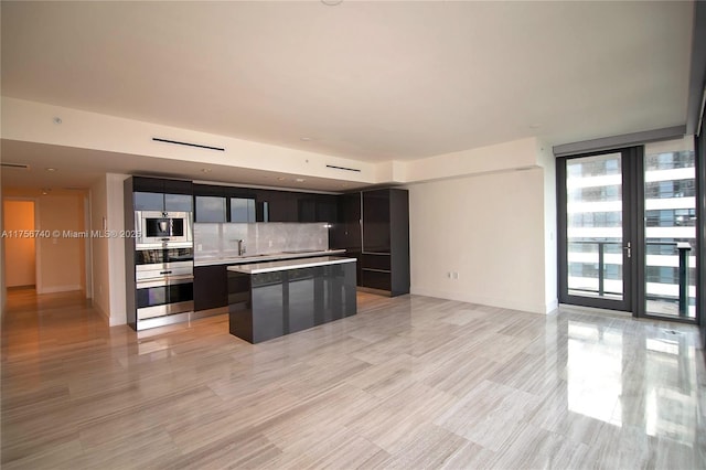 1451 Brickell Ave Unit 1201, Miami, FL 33131 - kitchen with oven, dark cabinets, a center island, decorative backsplash, and light countertops