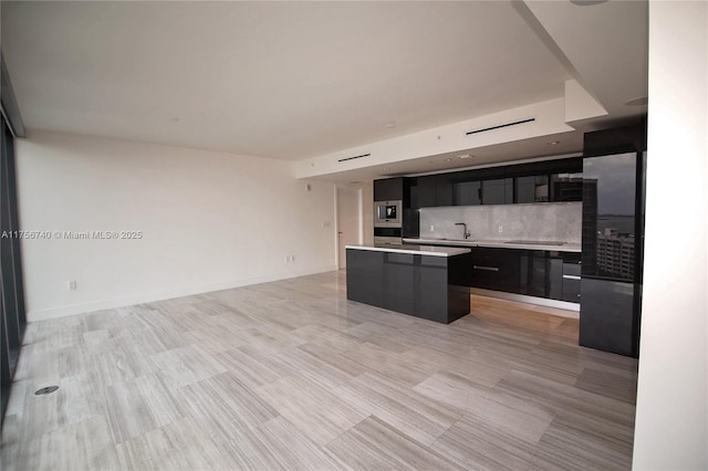 1451 Brickell Ave Unit 1201, Miami, FL 33131 - kitchen featuring dark cabinetry, a center island, light countertops, open floor plan, and decorative backsplash