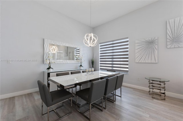 dining space with a notable chandelier, baseboards, and light wood-type flooring