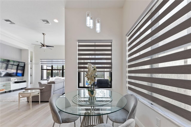 dining room with ceiling fan with notable chandelier, wood finished floors, visible vents, and baseboards