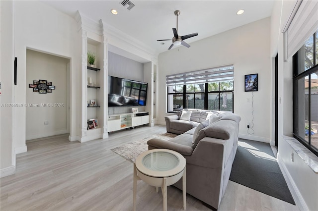 living area featuring light wood finished floors, visible vents, baseboards, and built in features