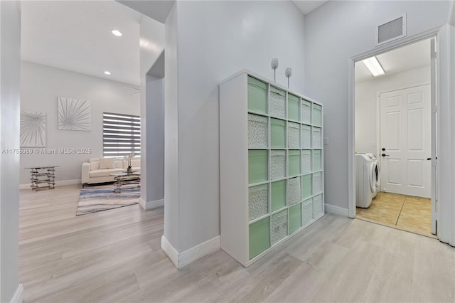 hallway with visible vents, baseboards, recessed lighting, light wood-style floors, and washing machine and dryer