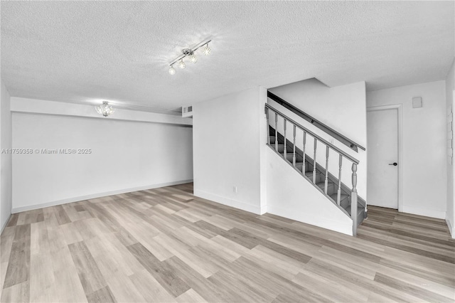 interior space with a textured ceiling, visible vents, baseboards, stairway, and light wood-type flooring