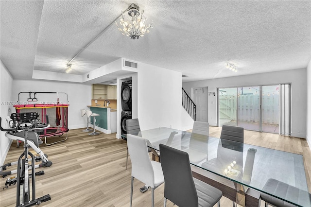 dining area with visible vents, stairway, stacked washer / drying machine, wood finished floors, and a textured ceiling