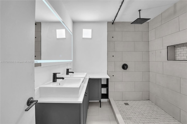 bathroom featuring tile patterned flooring, a tile shower, and vanity