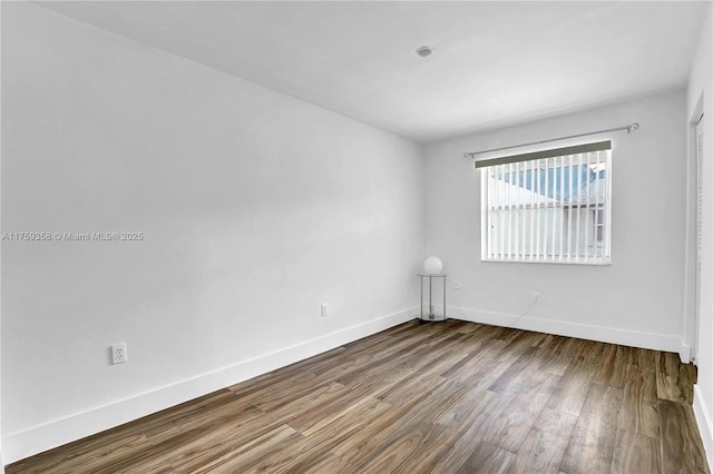 empty room featuring dark wood-type flooring and baseboards