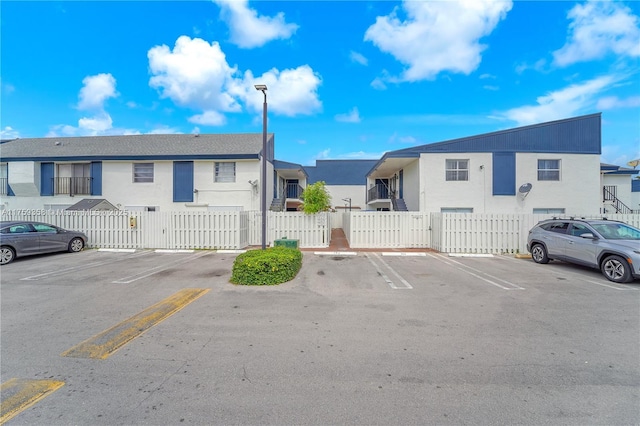 uncovered parking lot with a residential view, a gate, and fence