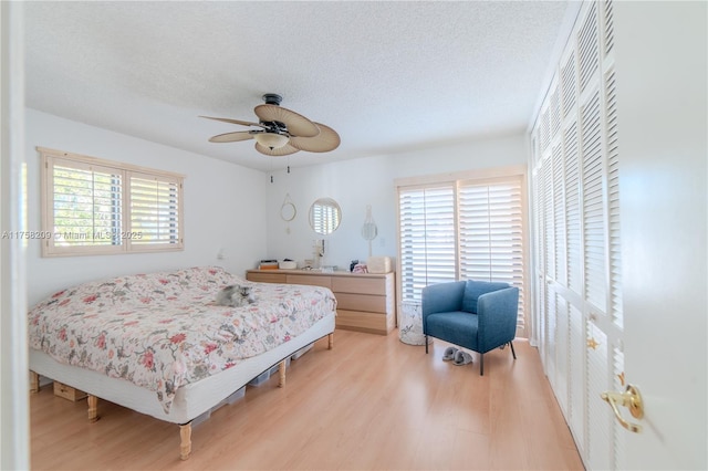 bedroom featuring a textured ceiling, a ceiling fan, and light wood-style floors