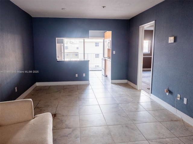 empty room with light tile patterned floors and baseboards