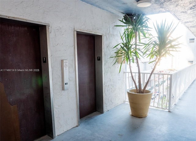 doorway to property with elevator and a balcony