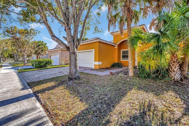 view of front of home with stucco siding, decorative driveway, and a garage