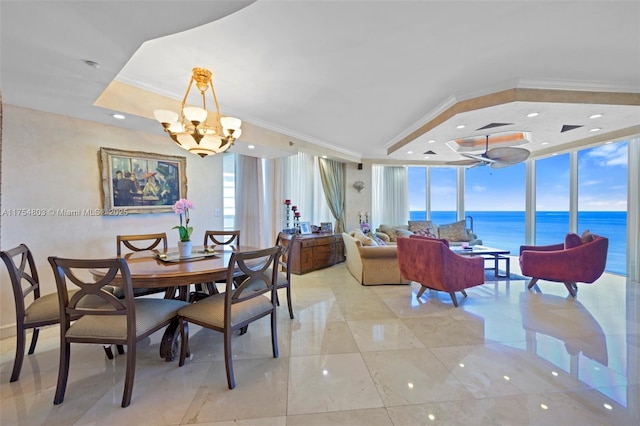 dining area with crown molding, a notable chandelier, a raised ceiling, a water view, and expansive windows