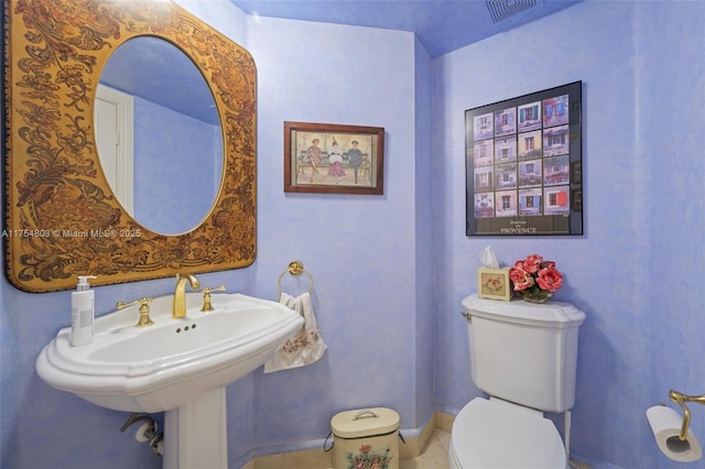 half bath featuring baseboards, visible vents, a sink, and toilet