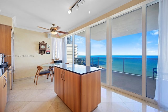 kitchen with brown cabinetry, a water view, ornamental molding, and modern cabinets