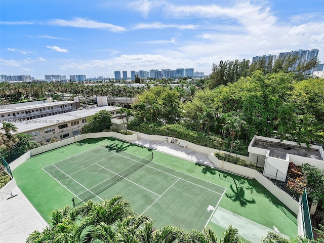 view of tennis court featuring fence and a city view