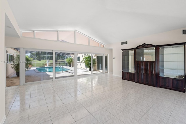 unfurnished living room with vaulted ceiling, light tile patterned floors, and baseboards