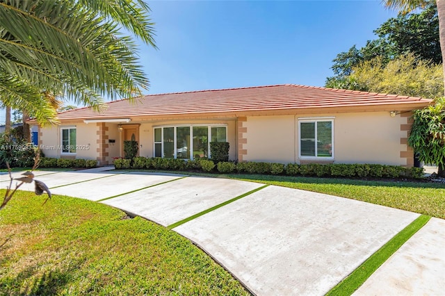 ranch-style house featuring a front yard, stucco siding, and a tile roof