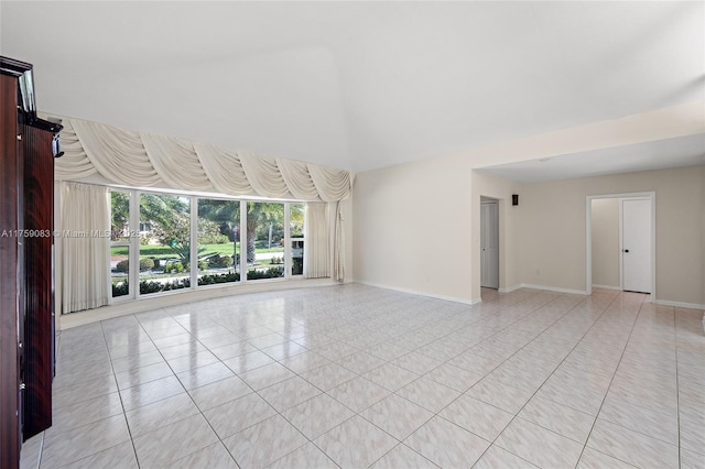unfurnished living room with light tile patterned flooring and baseboards