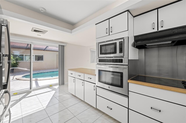 kitchen featuring under cabinet range hood, appliances with stainless steel finishes, white cabinetry, and light tile patterned flooring