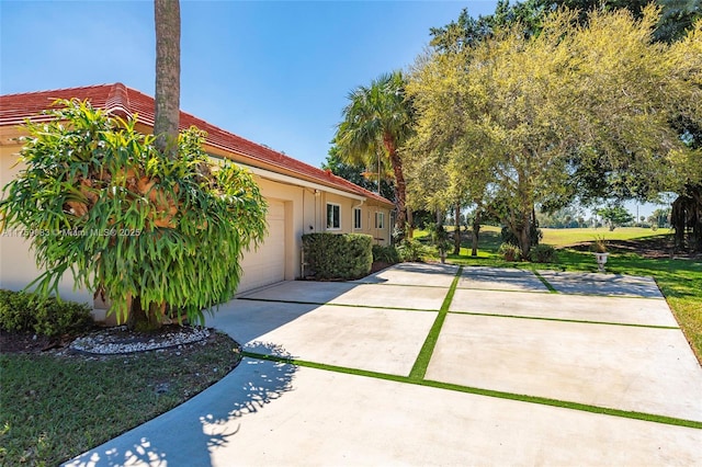 view of side of property featuring driveway, an attached garage, and a yard