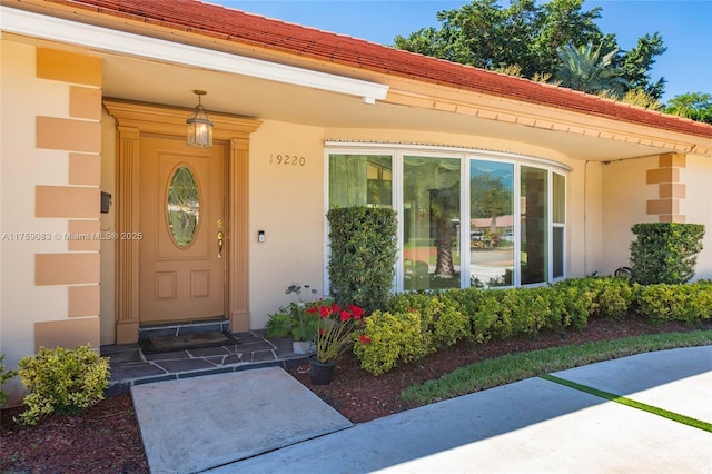 view of exterior entry with stucco siding and a tiled roof