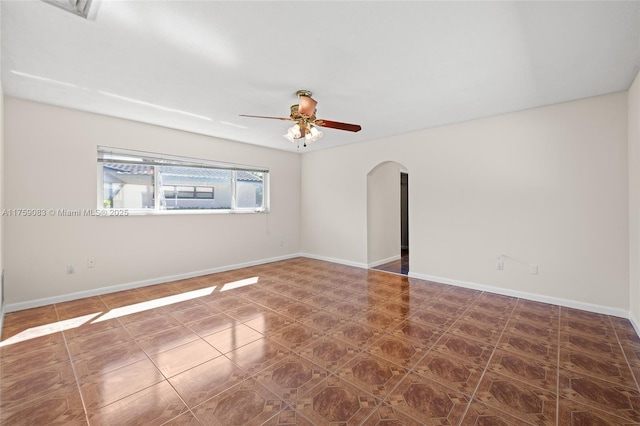 spare room with arched walkways, ceiling fan, and baseboards