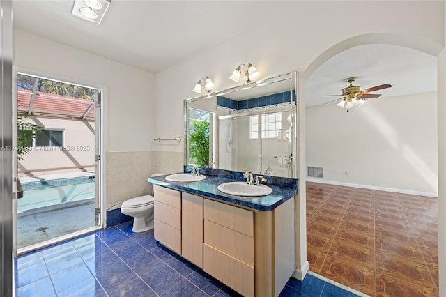 full bath featuring double vanity, an enclosed shower, ceiling fan, toilet, and tile patterned floors