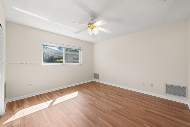 spare room featuring baseboards, wood finished floors, and a ceiling fan