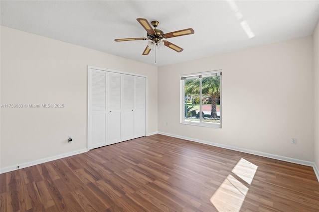 unfurnished bedroom featuring wood finished floors, baseboards, a closet, and ceiling fan