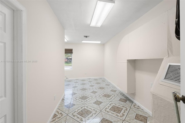 hallway with light tile patterned floors, baseboards, and visible vents